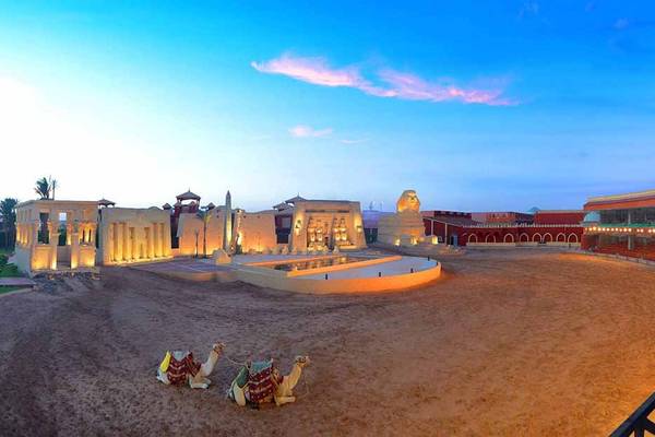 Außenansicht des Pickalbatros Alf Leila Wa Leila Resorts mit zwei Kamelen und einem Löwendenkmal bei Sonnenuntergang.