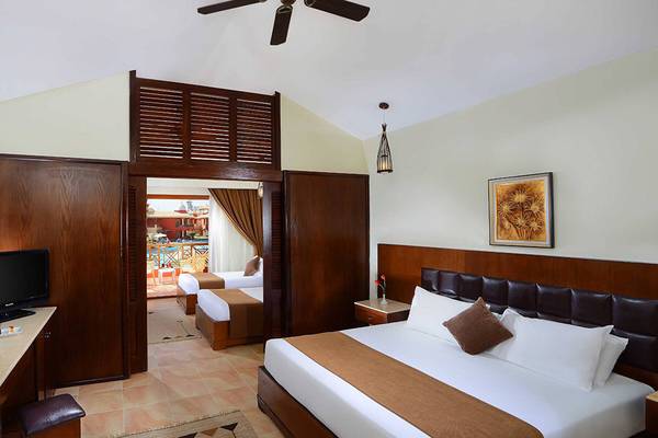 Hotelzimmer im Pickalbatros Alf Leila Wa Leila Resort mit Fernseher, Tisch, Spiegel und zwei Betten.