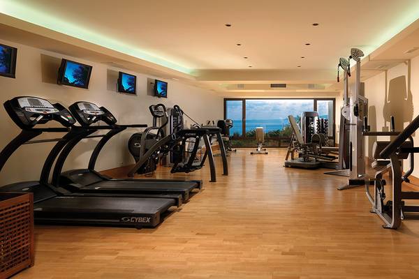Fitnesscenter im Porto Elounda Golf & Spa Resort mit modernen Laufbändern und Blick aufs Meer.