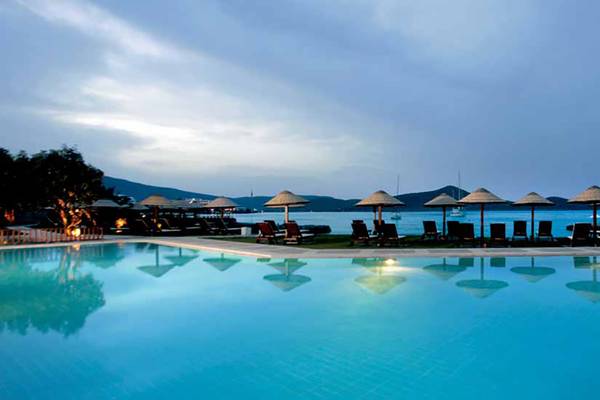 Außenansicht des Pools im Porto Elounda Golf & Spa Resort mit Sonnenschirmen und Liegestühlen.