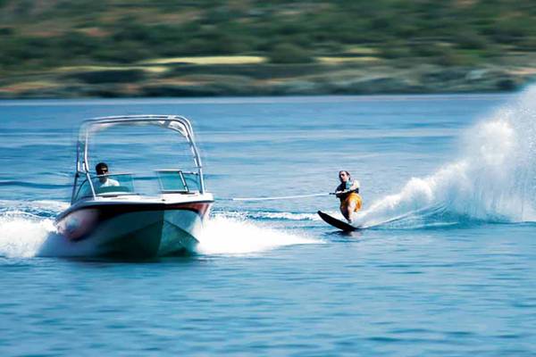 Personen auf einem Boot ziehen eine Wasserskifahrerin über das Wasser, Hotelname: Porto Elounda Golf & Spa Resort