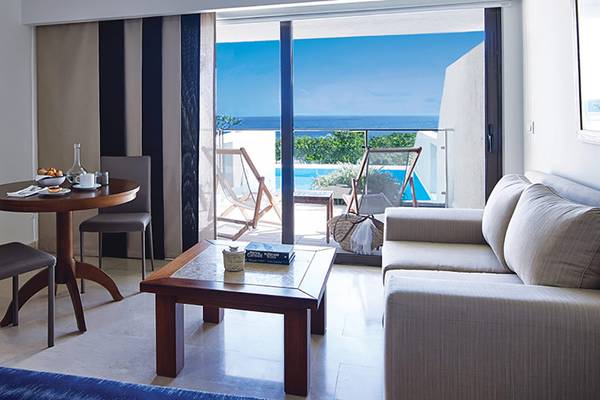 Wohnzimmer des Porto Elounda Golf & Spa Resorts mit Blick auf den Pool und das Meer.