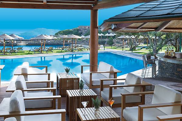 Außenbereich des Porto Elounda Golf & Spa Resorts mit Blick auf den Swimmingpool und die Bar.