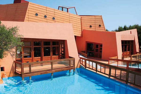 Außenansicht des Porto Elounda Golf & Spa Resorts mit Schwimmbad und Terrasse.