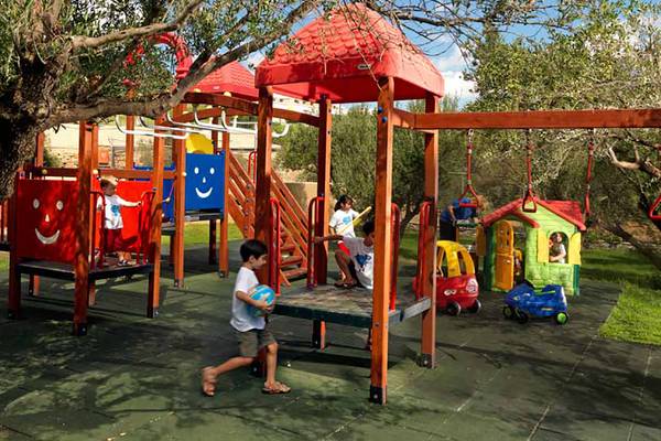 Kinder spielen auf einem Spielplatz im Freien des Porto Elounda Golf & Spa Resorts.