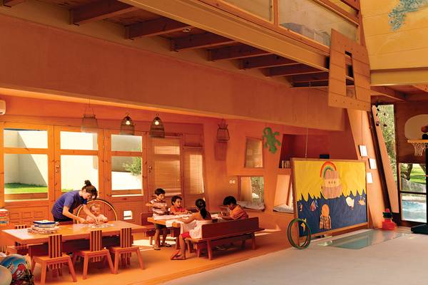 Im Kinderzimmer des Porto Elounda Golf & Spa Resorts sitzen Kinder an Tischen und spielen.