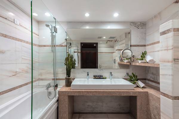 Badezimmer im Porto Elounda Golf & Spa Resort mit Badewanne, Waschbecken und Dusche.