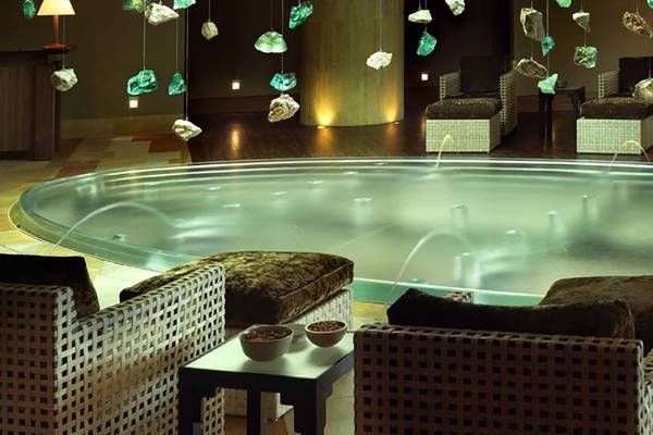 Wellnessbereich im Porto Elounda Golf & Spa Resort mit einem großen Wasserbecken und umliegenden Sitzmöbeln.