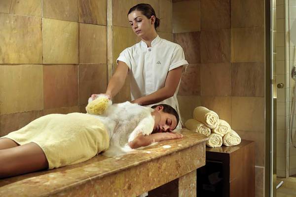Eine Frau im Spa-Bereich des Porto Elounda Golf & Spa Resorts, die eine Massagebehandlung genießt.