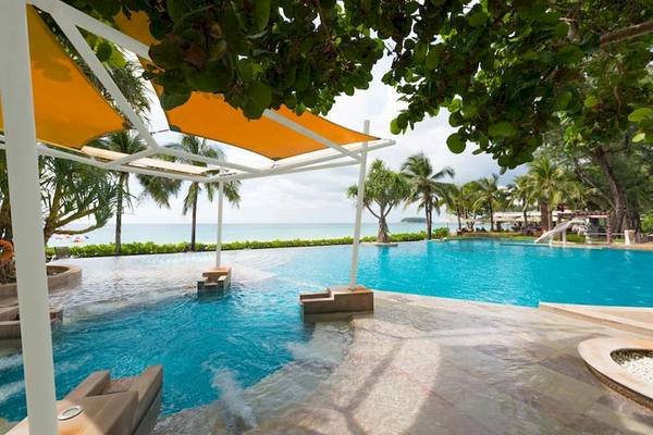 Pool des Katathani Phuket Beach Resorts mit gelben Sonnenschirmen und Blick aufs Meer.