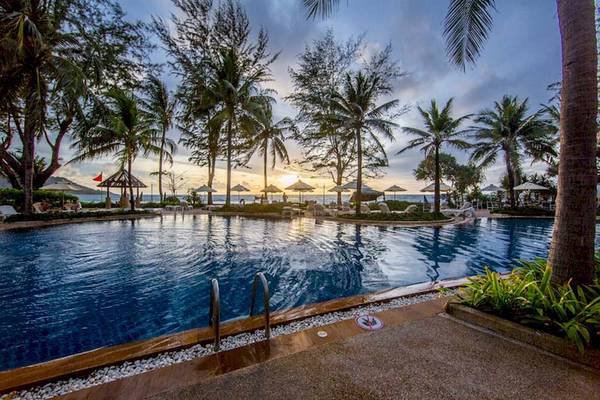 Pool des Katathani Phuket Beach Resorts am Abend mit Sonnenuntergang und Palmen