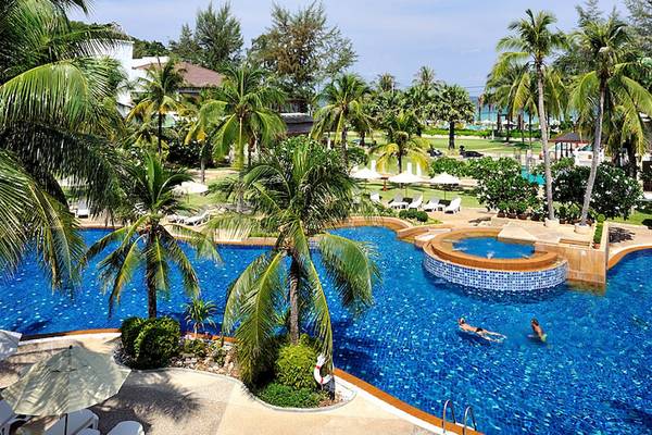 Außenansicht des Katathani Phuket Beach Resort Pools mit zwei Schwimmern und üppiger Palmenbepflanzung.