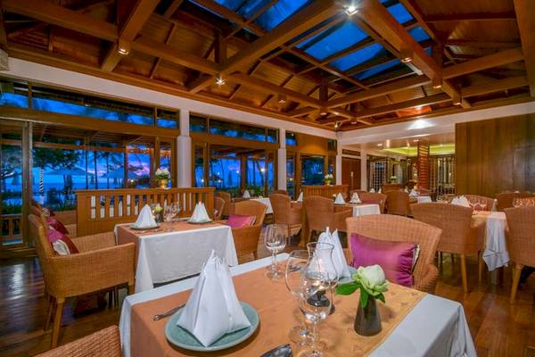 Innenansicht des Restaurants im Katathani Phuket Beach Resort mit Tischen, Stühlen und Meeresblick.