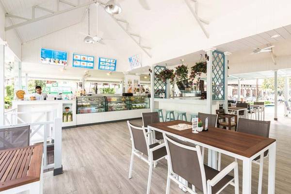 Innenansicht des Cafés im Katathani Phuket Beach Resort mit Tischen, Stühlen und Dekor.