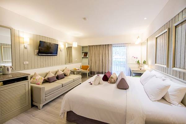Hotelzimmer im Katathani Phuket Beach Resort mit großem Bett, Sofa, Fernseher und Fenstern.