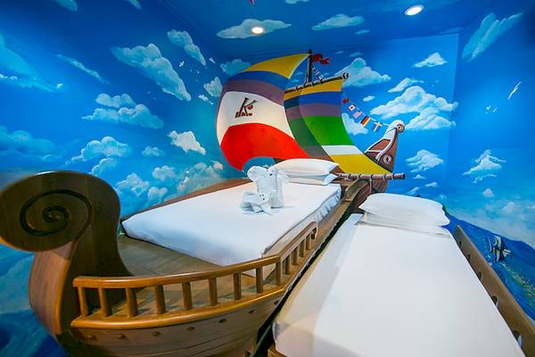 Doppelbett im Katathani Phuket Beach Resort, das als Schiff gestaltet ist, mit maritimem Wandbild.