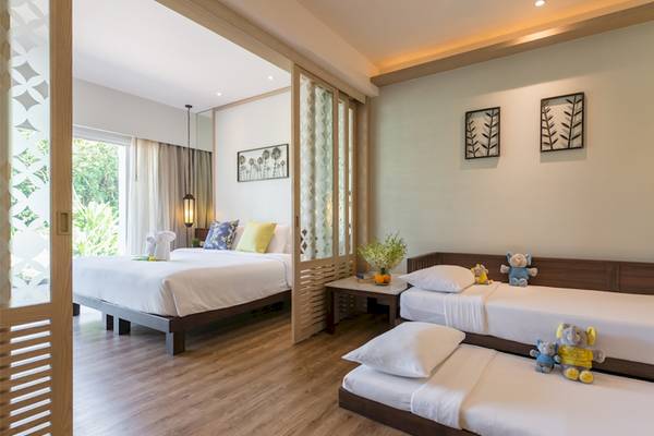 Innenansicht eines Zimmers im Katathani Phuket Beach Resort mit drei Betten und Dekofiguren.