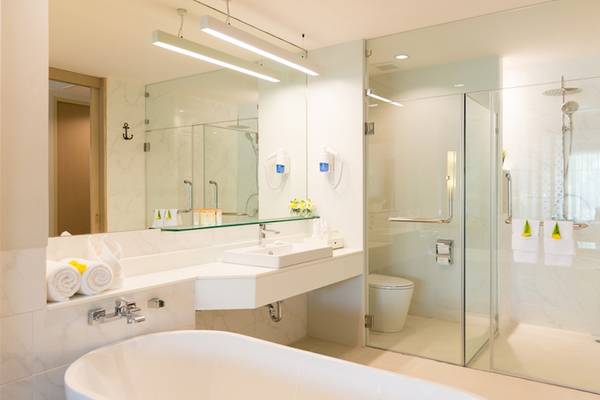 Badezimmer im Katathani Phuket Beach Resort mit Badewanne, Dusche und Waschbecken.