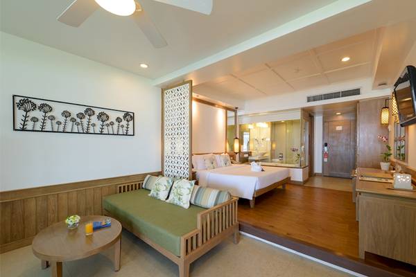 Innenansicht der Suite im Katathani Phuket Beach Resort mit Bett, Sofa und Schreibtisch.