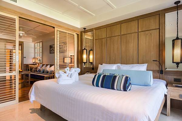 Schlafzimmer im Katathani Phuket Beach Resort mit gemustertem Kissen und frischen Handtüchern.