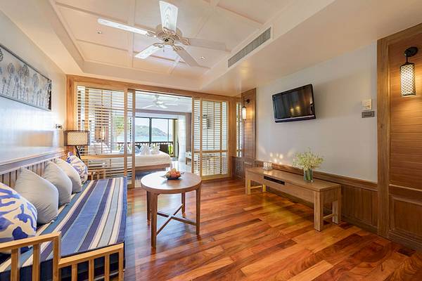 Inneneinrichtung eines Zimmers im Katathani Phuket Beach Resort mit Holzboden, Möbeln und Fernseher.
