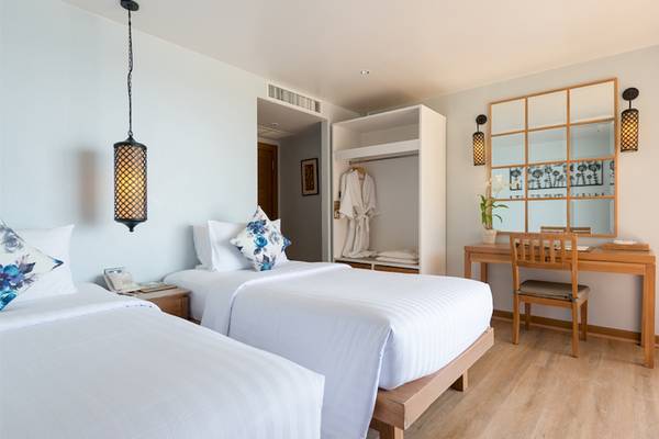 Schlafzimmer im Katathani Phuket Beach Resort mit zwei Betten, Schreibtisch und Spiegel.