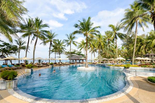 Ein großer Swimmingpool im Katathani Phuket Beach Resort mit vielen Palmen und Sonnenliegen.