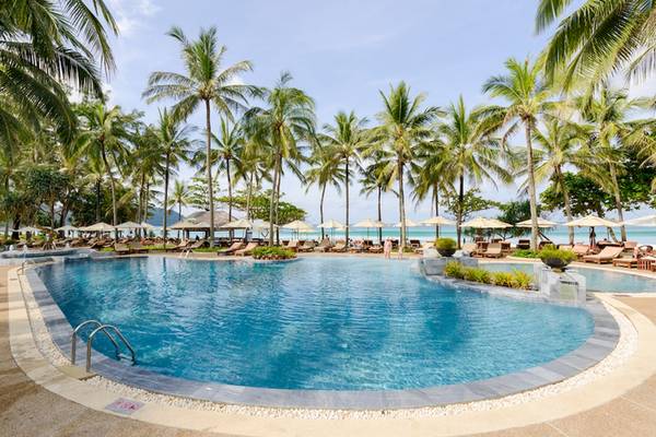 Außenpoolbereich des Katathani Phuket Beach Resorts mit Palmen und Sonnenliegen.