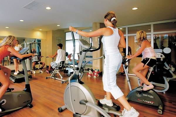 Mehrere Personen trainieren im Fitnessstudio auf verschiedenen Geräten.