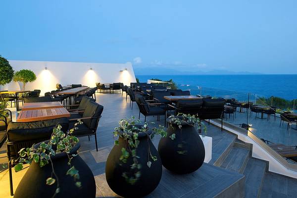 Außenbereich des Dimitra Beach Hotel & Suites mit Blick auf das Meer und Möbeln.