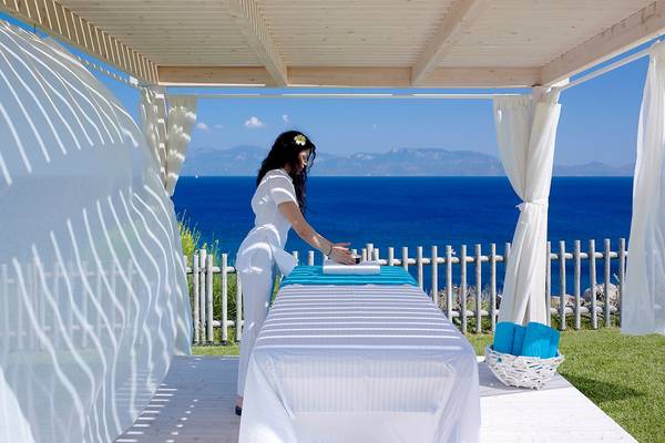 Massage-Therapeutin bereitet Massagetisch im Freien auf Dimitra Beach Hotel vor