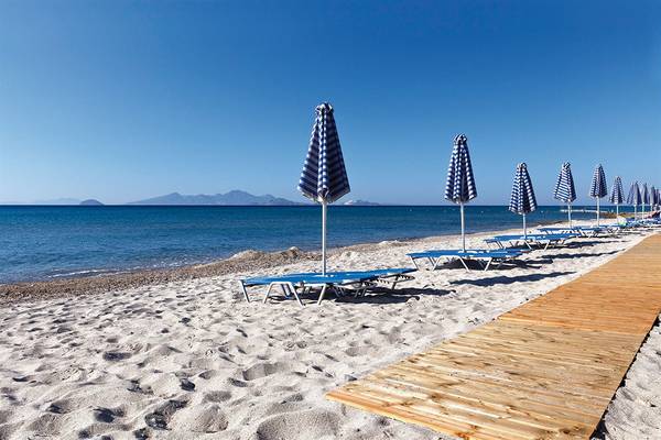 Strandszene mit Sonnenliegen und Sonnenschirmen am Atlantica Mikri Poli Kos Hotel