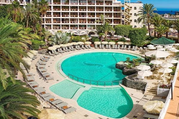 Luftaufnahme des Swimmingpool-Bereichs des Seaside Sandy Beach Hotels mit vielen Liegestühlen und Sonnenschirmen.