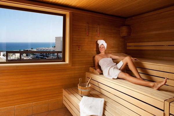 Frau im Bademantel in der Sauna mit Blick auf das Meer im Seaside Sandy Beach Hotel.