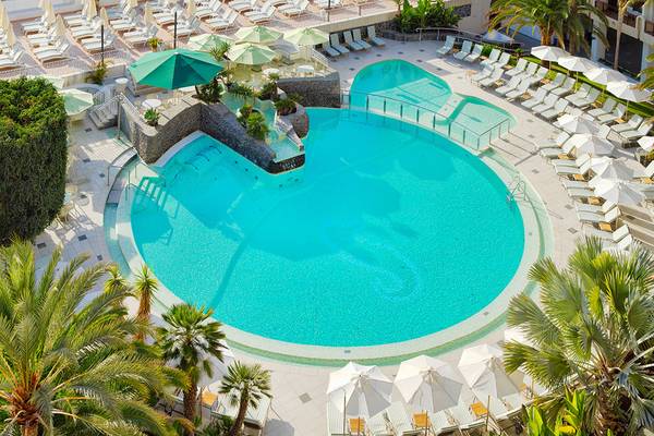 Luftaufnahme des Pools im Seaside Sandy Beach Hotel mit vielen Liegen und Sonnenschirmen.