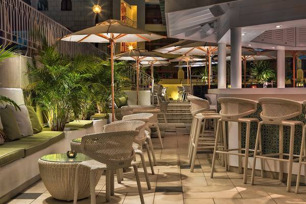 Terrasse des Seaside Sandy Beach Hotels mit Stühlen, Tischen und Schirmen bei Nacht