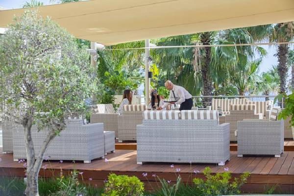Ein Mann serviert Getränke auf einer Terrasse des Aquamare Beach Hotel & Spa.