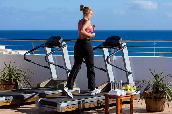 Frau läuft auf einem Laufband auf der Terrasse mit Blick auf das Meer.