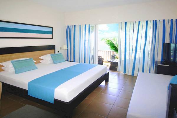 Doppelbett mit Balkon im Pearle Beach Resort & Spa mit Blick auf den Ozean.