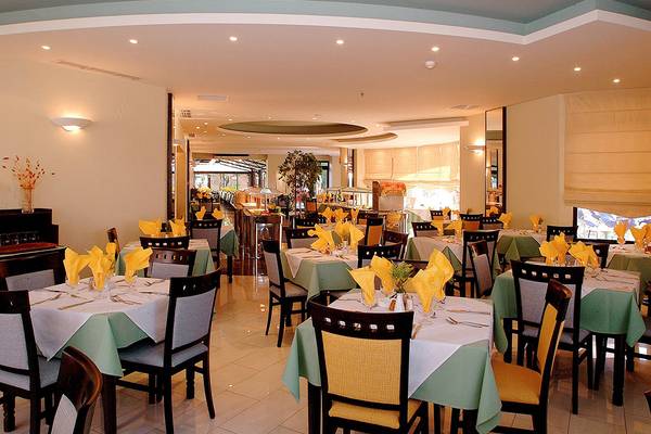 Innenansicht des Restaurants im Pearle Beach Resort mit gedeckten Tischen und Stühlen.