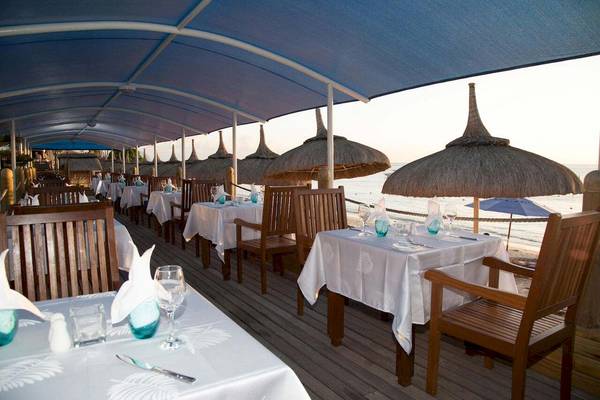Außenrestaurant im Pearle Beach Resort & Spa mit Blick auf das Meer und Strohdächern.