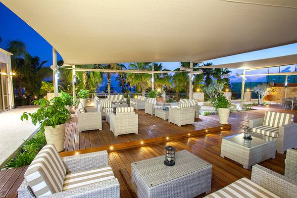 Terrasse des Aquamare Beach Hotel & Spa mit Lounge-Sesseln und Tischen bei Nacht