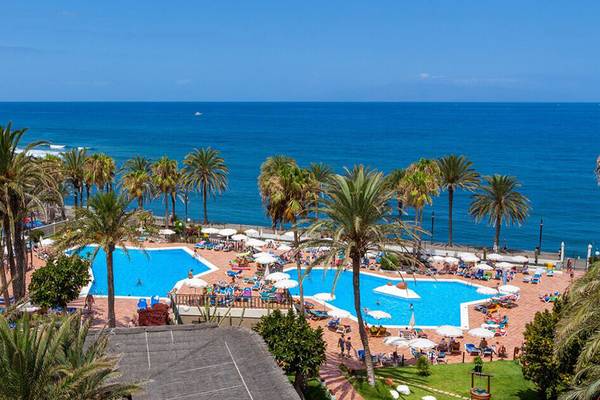 Aussicht auf das Sol Tenerife Hotel und den Poolbereich mit Meerblick und vielen Sonnenschirmen.