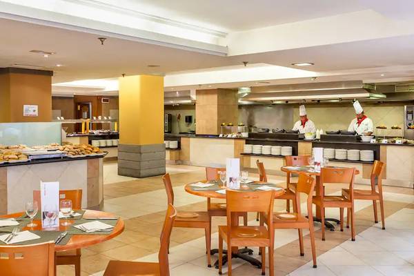 Innenansicht des Restaurants im Sol Tenerife Hotel mit gedeckten Tischen und Köchen hinter der Theke.