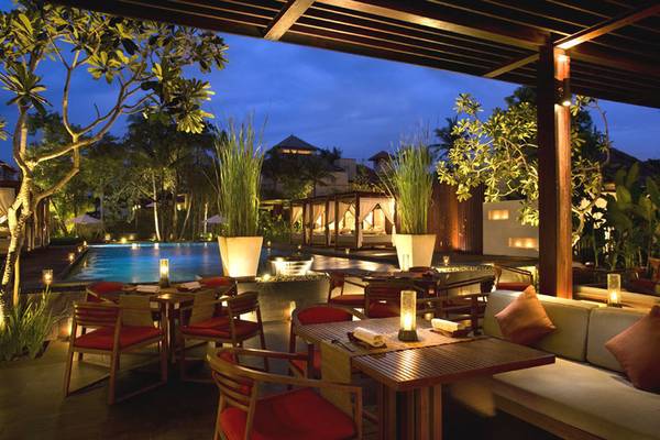 Außenbereich des Conrad Bali Resort & Spa bei Nacht mit beleuchteten Tischen und Stühlen.