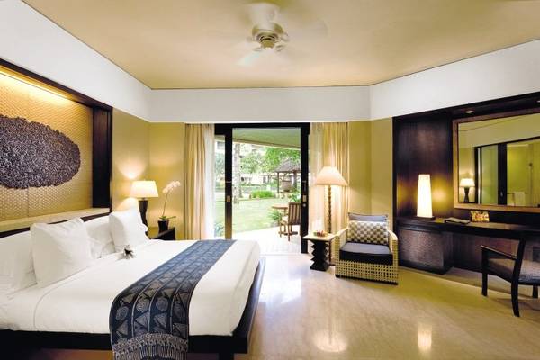 Schlafzimmer im Conrad Bali Resort & Spa mit großem Bett und Blick auf den Garten.