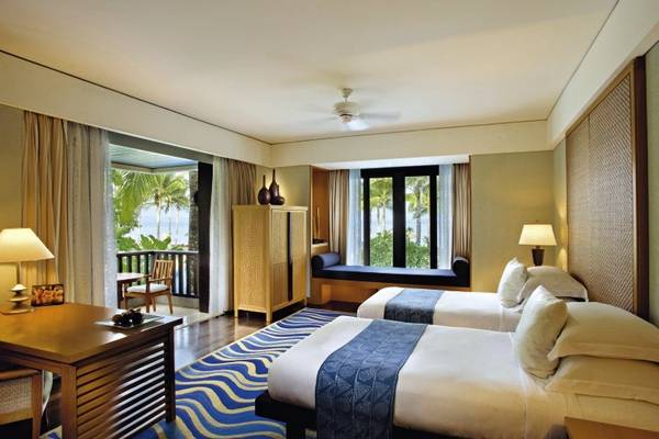 Schlafzimmer im Conrad Bali Resort & Spa mit zwei Betten, Fenstern und einem Balkon.