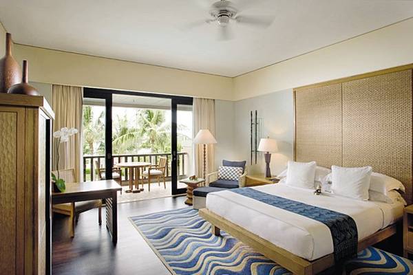 Schlafzimmer im Conrad Bali Resort & Spa mit Blick auf die Terrasse und den Garten.