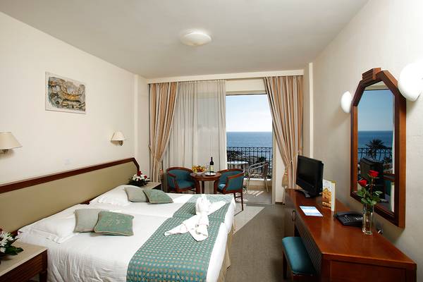 Doppelzimmer im Aquamare Beach Hotel mit Meerblick, Bett, Fernseher, Tisch und Balkonmöbeln.