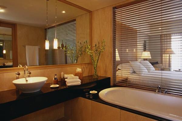 Badezimmer im Conrad Bali Resort & Spa mit Badewanne, Waschbecken und Spiegel